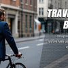 A man wearing a blue suit is carrying a black backpack while riding a bicycle on a city street.