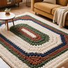 A knitted rug featuring a geometric pattern in earthy tones of beige, olive green, brown, and navy blue.