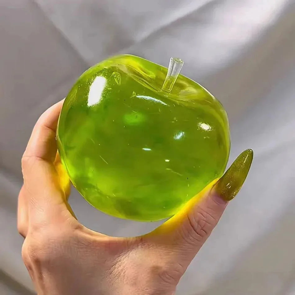 Eine Hand hält einen leuchtend grünen, durchsichtigen, apfelförmigen Stressball mit einer klaren Kunststoffspitze.