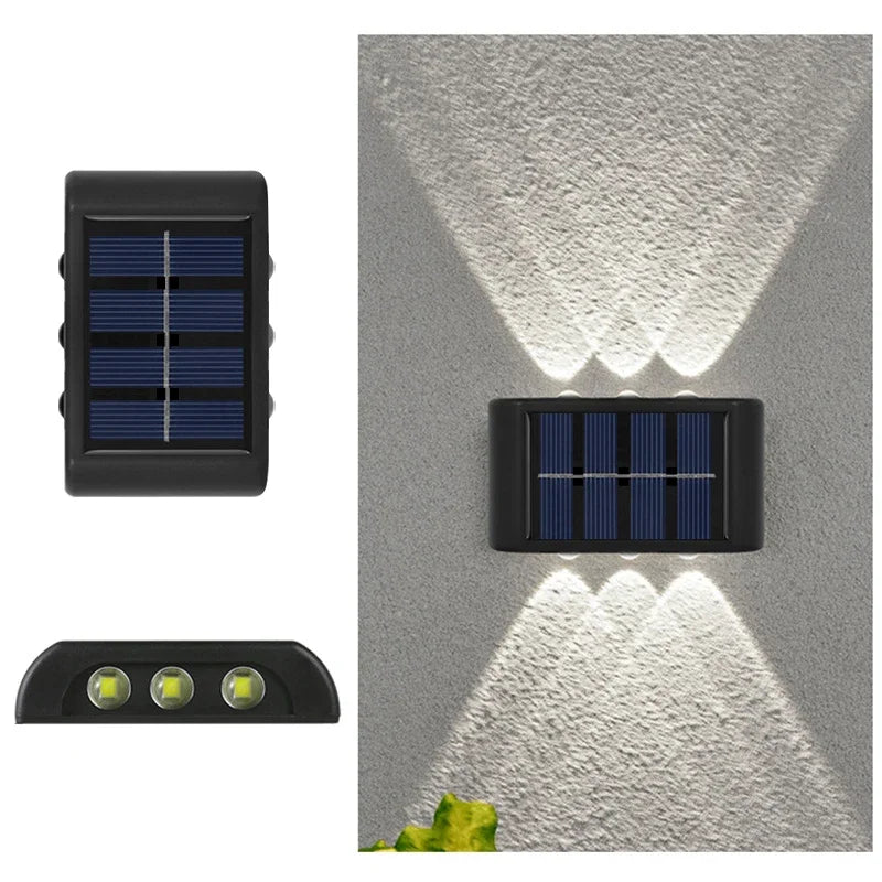 A solar powered outdoor wall light with upward and downward illumination mounted on a gray textured surface.