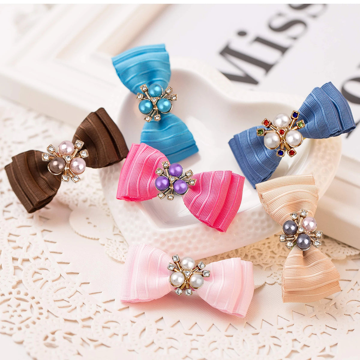 A collection of colorful silk ribbons tied into bows adorned with pearlized resin flower beads for DIY jewelry.