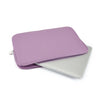 A purple laptop sleeve with a zipper closure placed next to a silver laptop.
