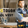 A man wearing a yellow and black tool vest in a workshop setting.