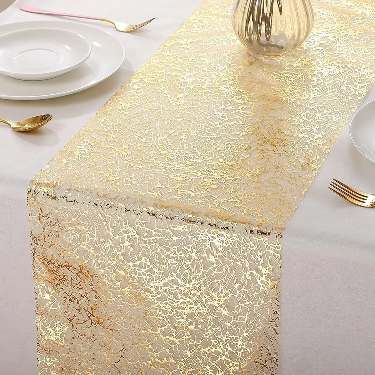 Metallic gold glitter table runner displayed on a white tablecloth with tableware.