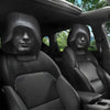 Two black car headrest covers with sculpted hoods are shown inside a vehicle cabin.