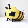 A yellow soft plush doll resembling a bee with black and white markings.