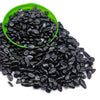 A pile of black tumbled crystal stone chips in a green bowl.