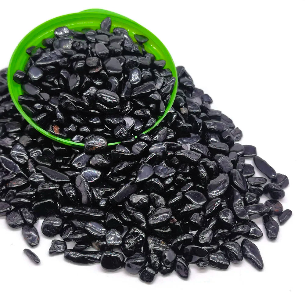 A pile of black tumbled crystal stone chips in a green bowl.