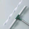 A silicone scraper broom and squeegee with white bristles and a green handle, shown diagonally on a light gray surface.