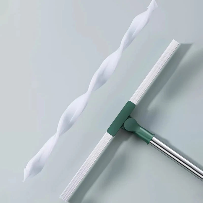 A silicone scraper broom and squeegee with white bristles and a green handle, shown diagonally on a light gray surface.