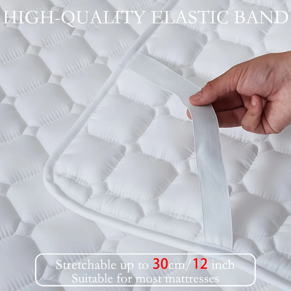 Eine Hand dehnt ein hochwertiges elastisches Band auf einem weißen gesteppten Matratzenschutz.