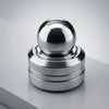 A polished silver kinetic metal desk spinner with a smooth spherical top and stacked rings.