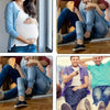 A woman wearing a white top and blue jacket holds her pregnant belly, next to a pair of adjustable metal jeans button extende