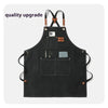 Black chef apron with cross-back straps and tool pockets featuring a smartphone and scissors.