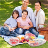 A family is shown outdoors with reusable elastic food covers on the grass.