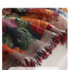 Close-up of a romantic floral jacquard sofa blanket with fringed tassels in rich jewel tones.