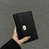 A hand holds a sleek black compact wallet featuring a gold cloud emblem.