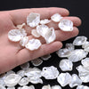 A hand holds a collection of white acrylic pearl spacer beads for jewelry making