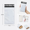 A white self-sealing mailing bag with a black header, shown next to a ruler for scale.