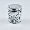 A glass jar with a silver lid filled with metallic foil flakes for crafting