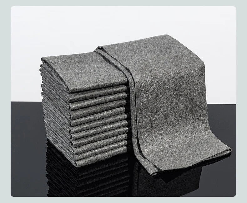 A stack of gray reusable microfiber cleaning cloths lying on a reflective surface.
