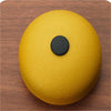 A round, golden percussion instrument with a black center, resting on a wooden surface.