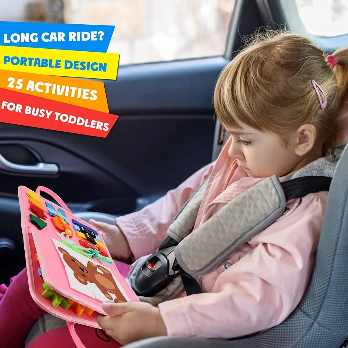 A toddler is engaging with a pink Montessori busy board activity in the seat of a car.