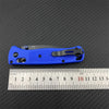 A blue ultralight EDC folding knife with a black handle and drop point blade is shown next to a ruler.