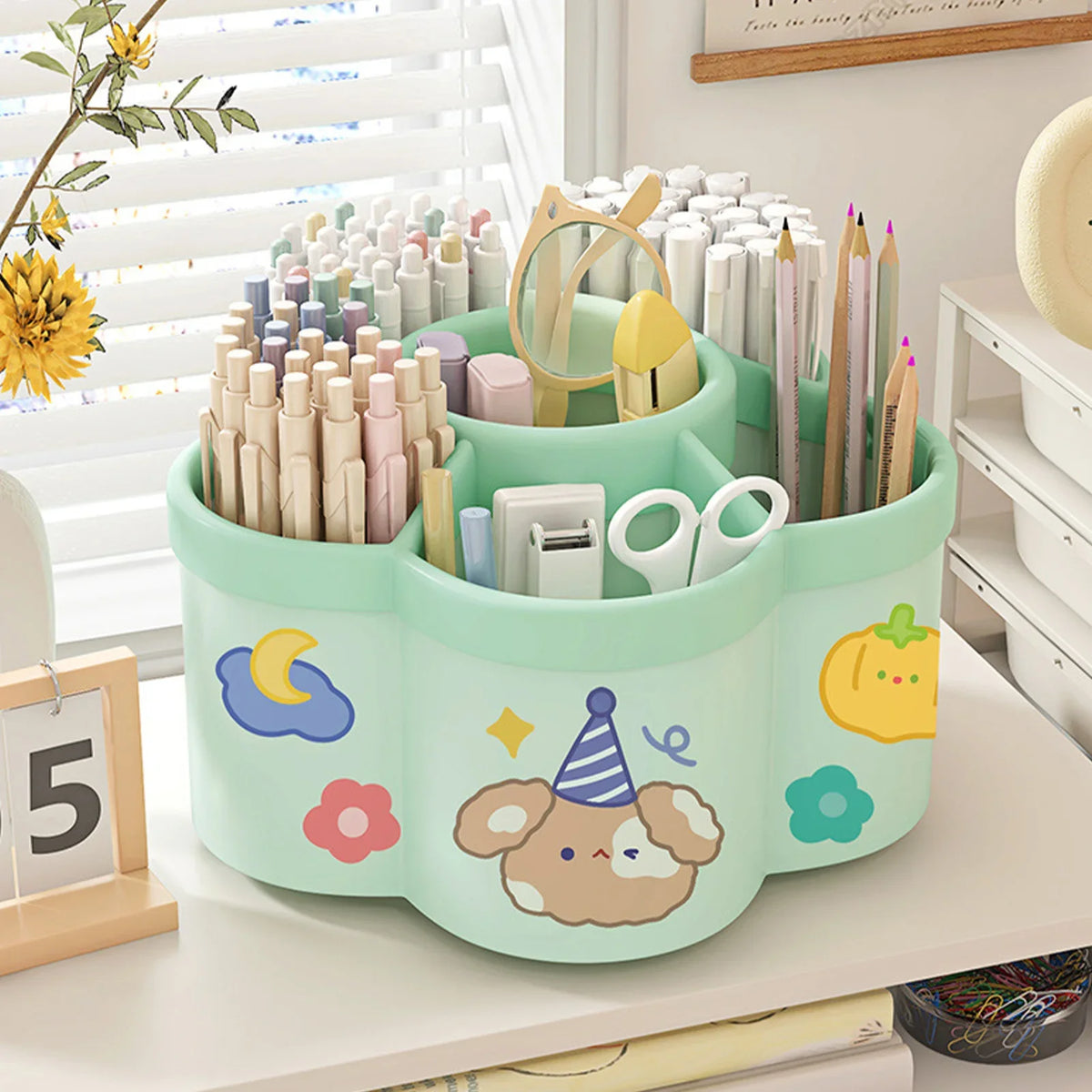 A light green rotating desk organizer holding various pens, pencils, and supplies with cute floral designs.