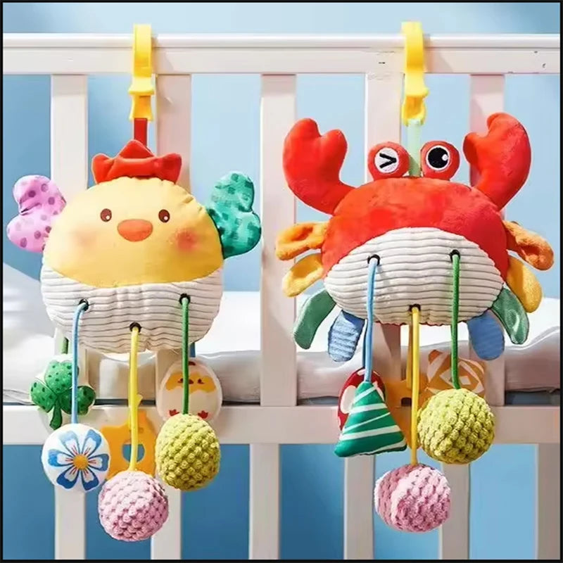 A colorful hanging crab sensory toy with a rattle and teether is displayed against a white crib railing.