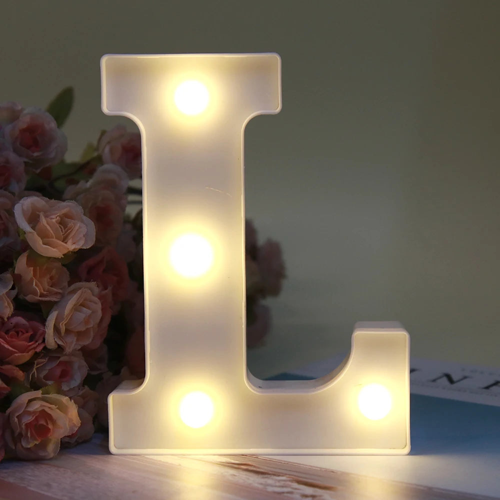 Lumière nocturne alphabet LED blanche luminescente en forme de lettre L posée sur une surface en bois.