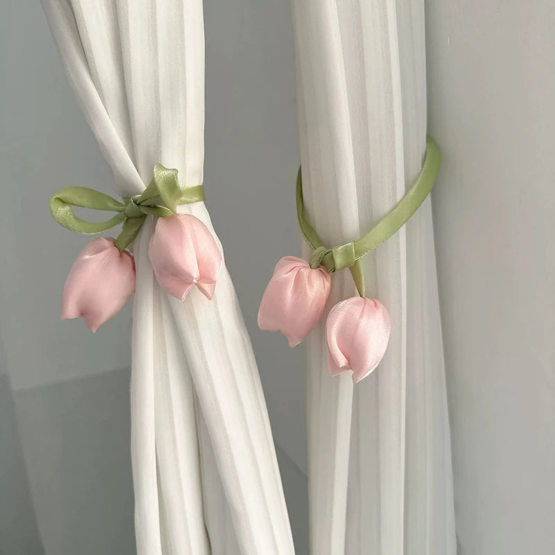 A set of pink tulip flower straps used as decorative tie backs on white curtains.