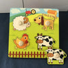 Un ensemble de blocs Montessori en bois avec des animaux de ferme comme une brebis, un chien, un poulet et une vache sur fond