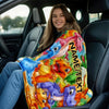 A young woman is sitting in a car, holding a colorful personalized dinosaur blanket with various dinosaurs and text on it.