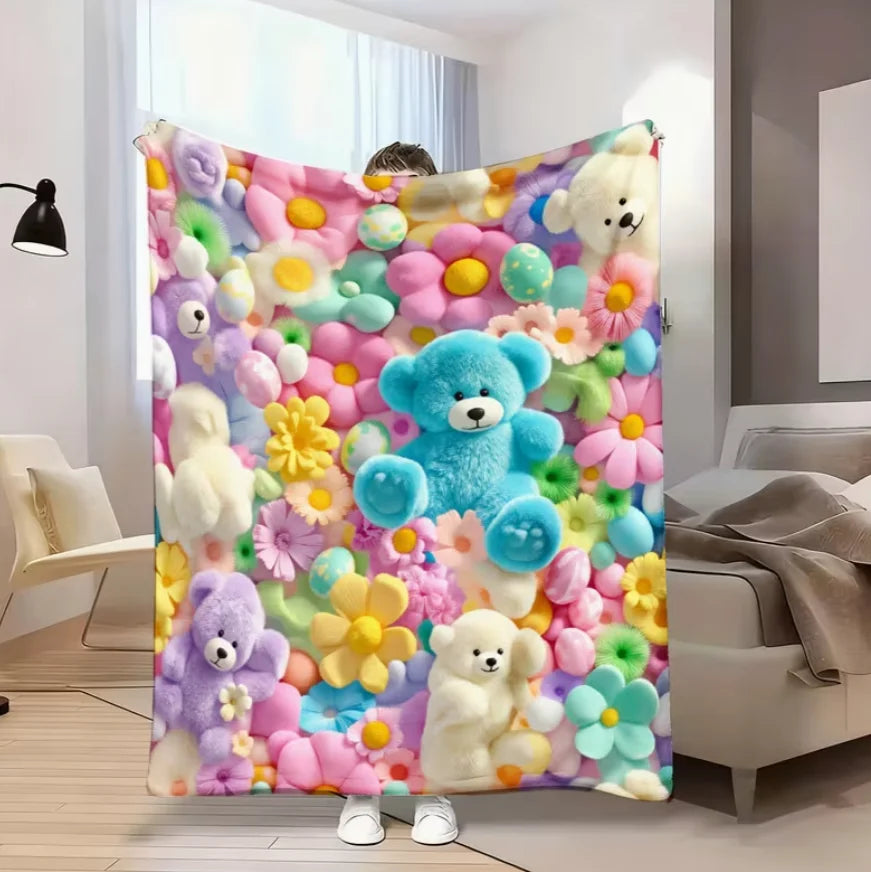 A colorful flannel throw blanket featuring various pastel-colored teddy bears and floral patterns.