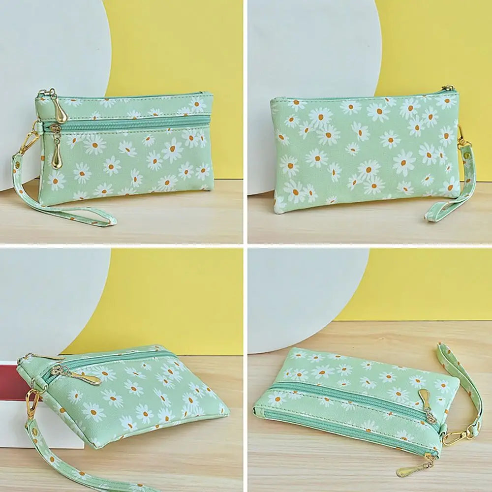 A set of light green PU leather wristlet wallets with a white daisy print and gold hardware shown from multiple angles.