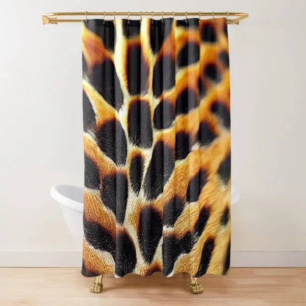 A leopard print shower curtain hanging from a gold rod.