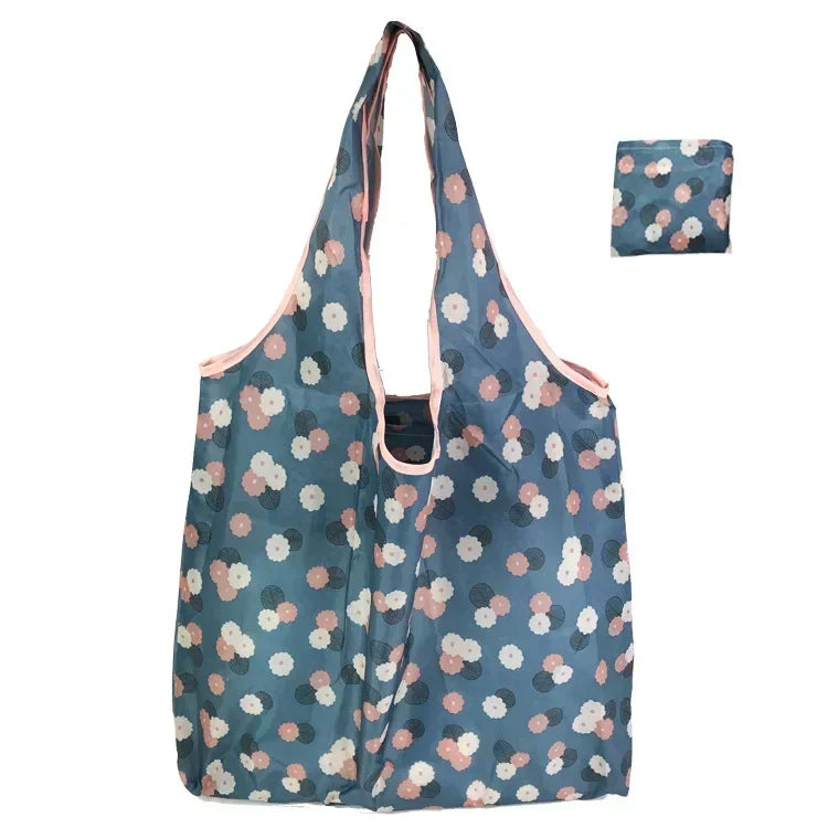A light blue floral shopping tote bag with a pink trim and matching patterned pouch.
