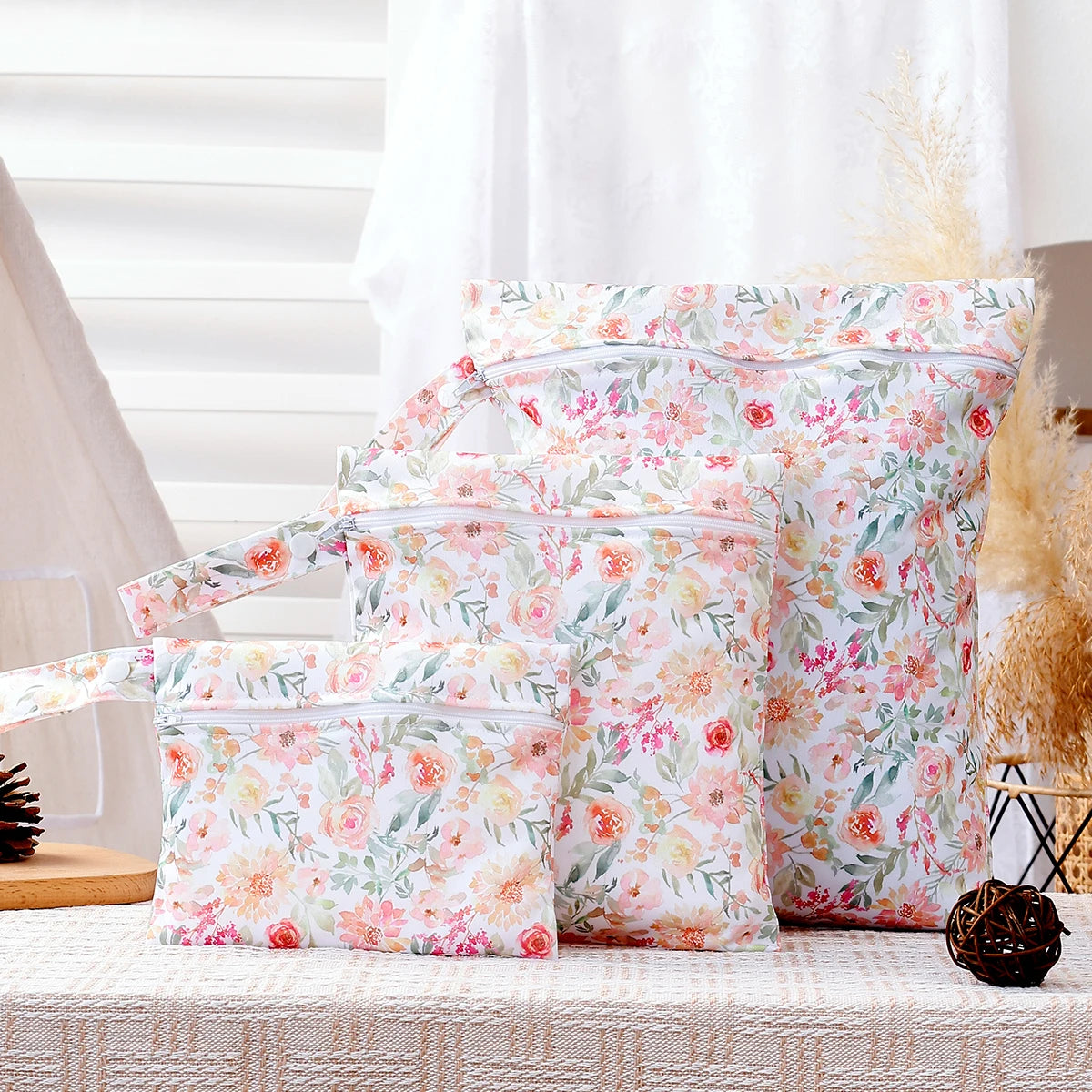 A set of reusable floral patterned waterproof wet bags with hanging hooks displayed on a white surface.
