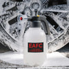 A white hand pump foam sprayer bottle with a black pump and nozzle is shown on a snowy surface.