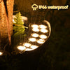 A close-up of an IP66 waterproof LED garden light illuminating a fern in a dark, wet environment.