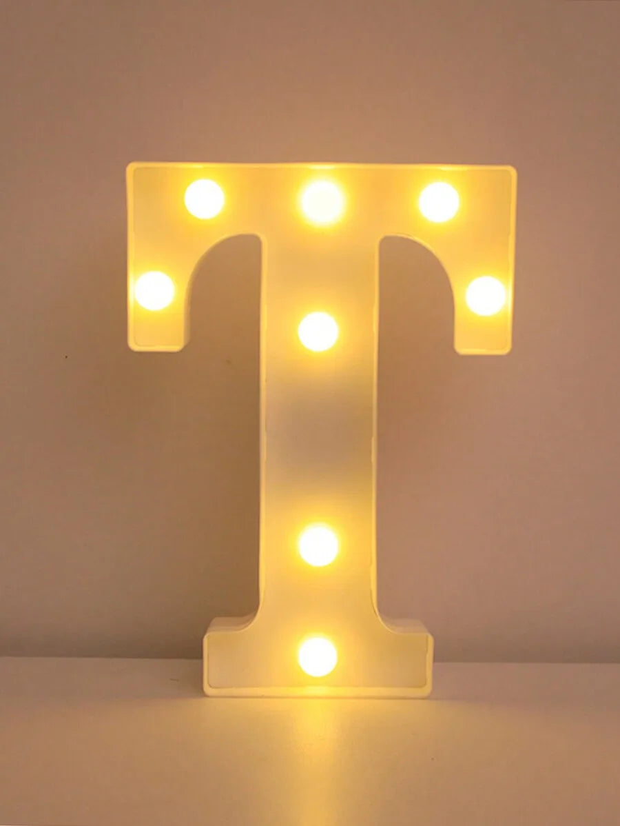 A glowing yellow LED letter T night light with multiple illuminated dots on a white surface.