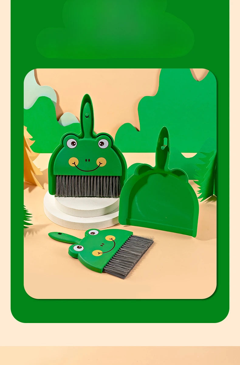 A green cartoon broom and dustpan set with a frog design on a light background.