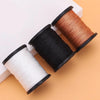 Three spools of heavy duty nylon thread in white, black, and brown resting on an orange surface.