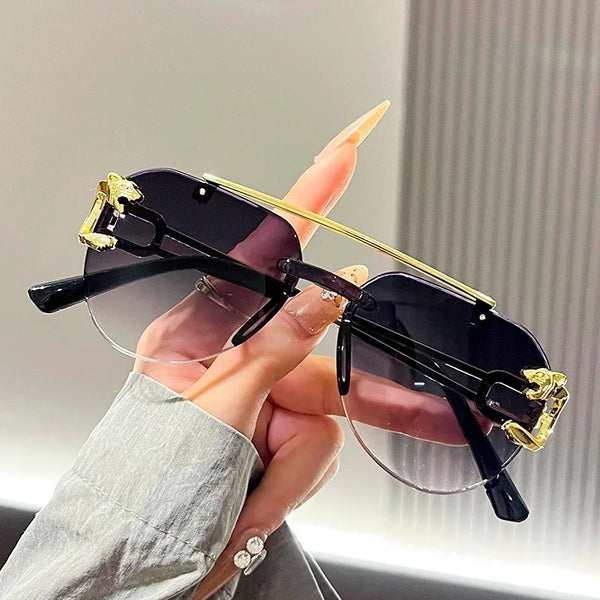 A hand holds a pair of black gradient UV protection sunglasses with gold accents against a light background.