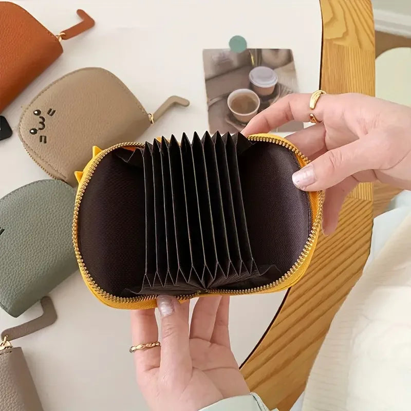 A hand holds a brown and yellow cartoon cat-shaped PU leather card wallet.