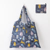 A reusable shopping tote bag featuring a pattern of cats in various poses and colors.