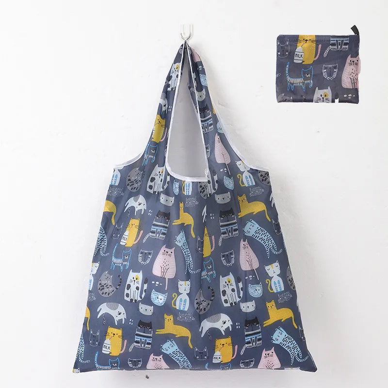 A reusable shopping tote bag featuring a pattern of cats in various poses and colors.