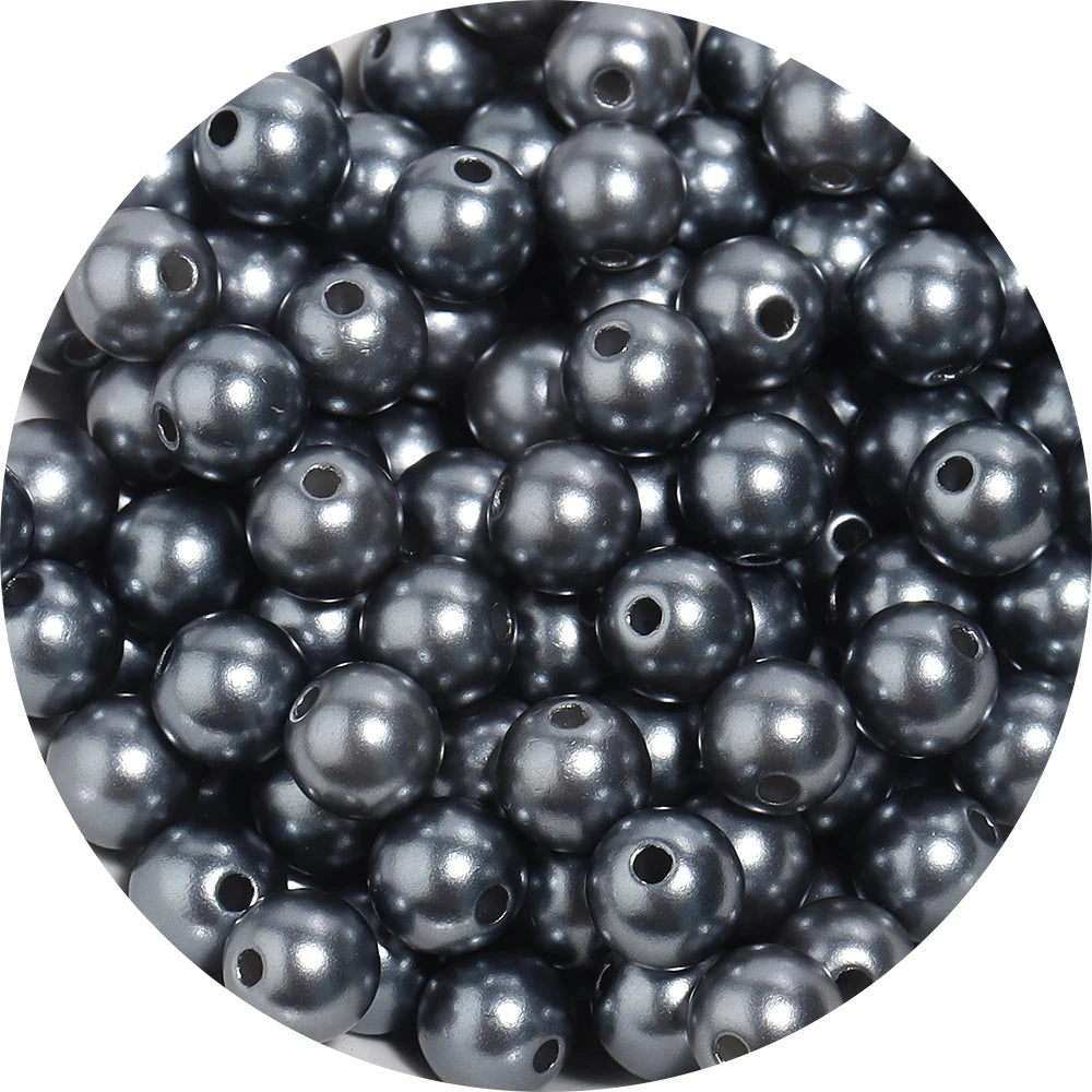 A close-up view of small, round, dark gray imitation pearl beads for jewelry making.