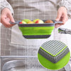 Un panier de drainage en silicone utilisé pour rincer des fruits sous l'eau courante.